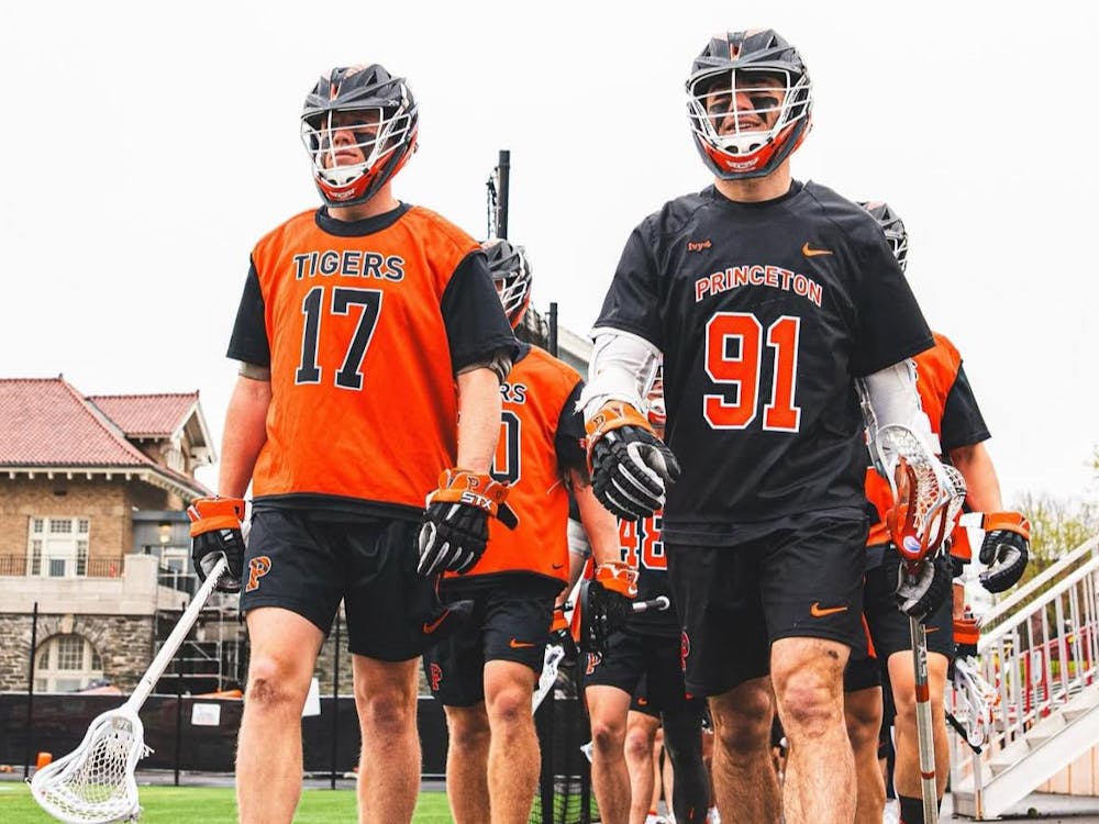 A group of men wearing orange and black jerseys walking on a grass field.