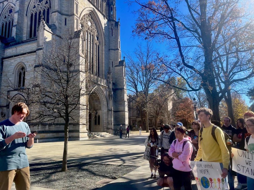 Group of students with sign standing outside a large stone Chapel. 