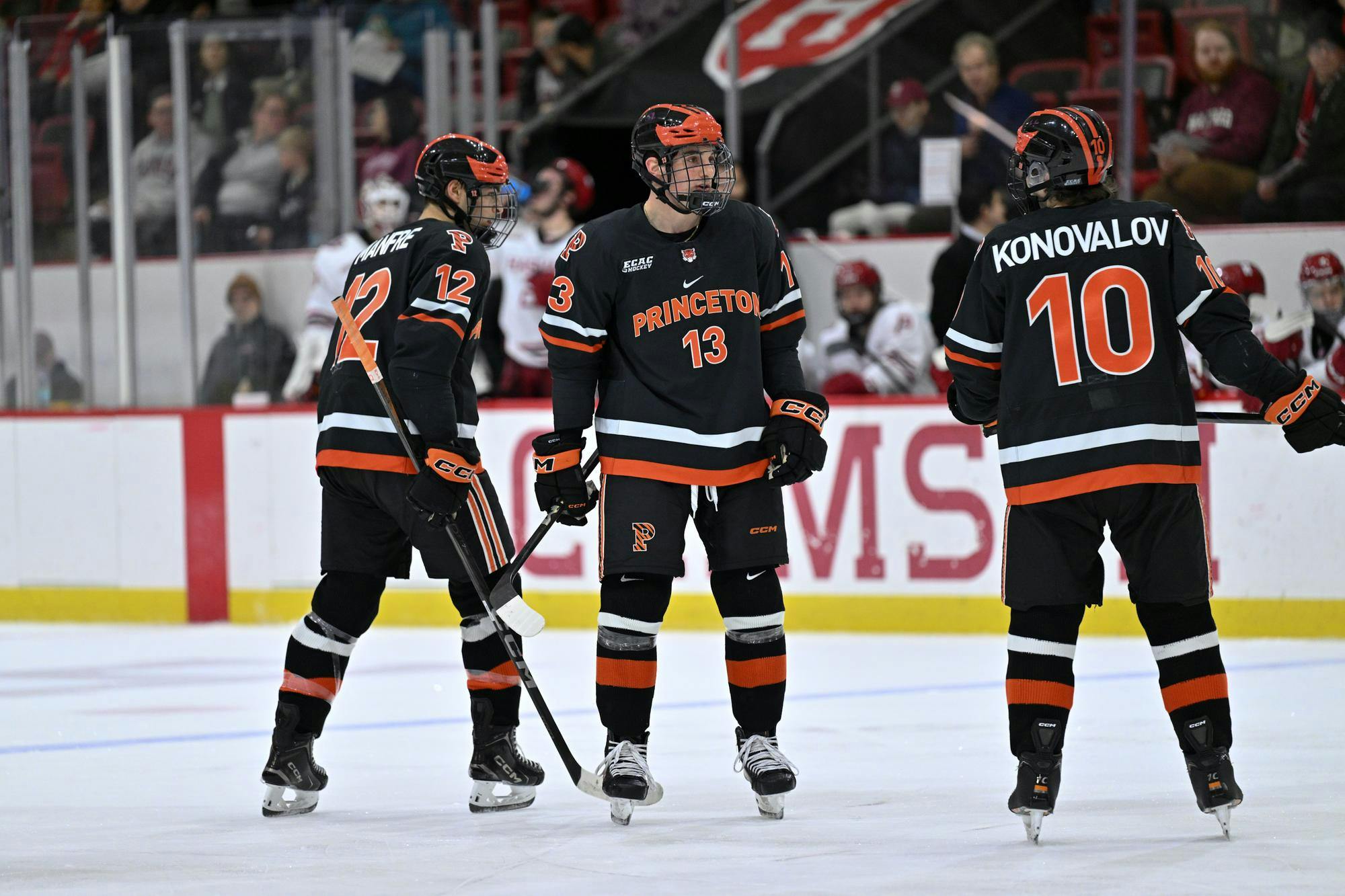 Three men standing on an ice hockey rink. 