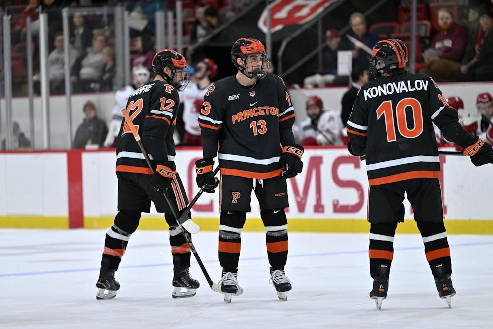 Three men standing on an ice hockey rink. 