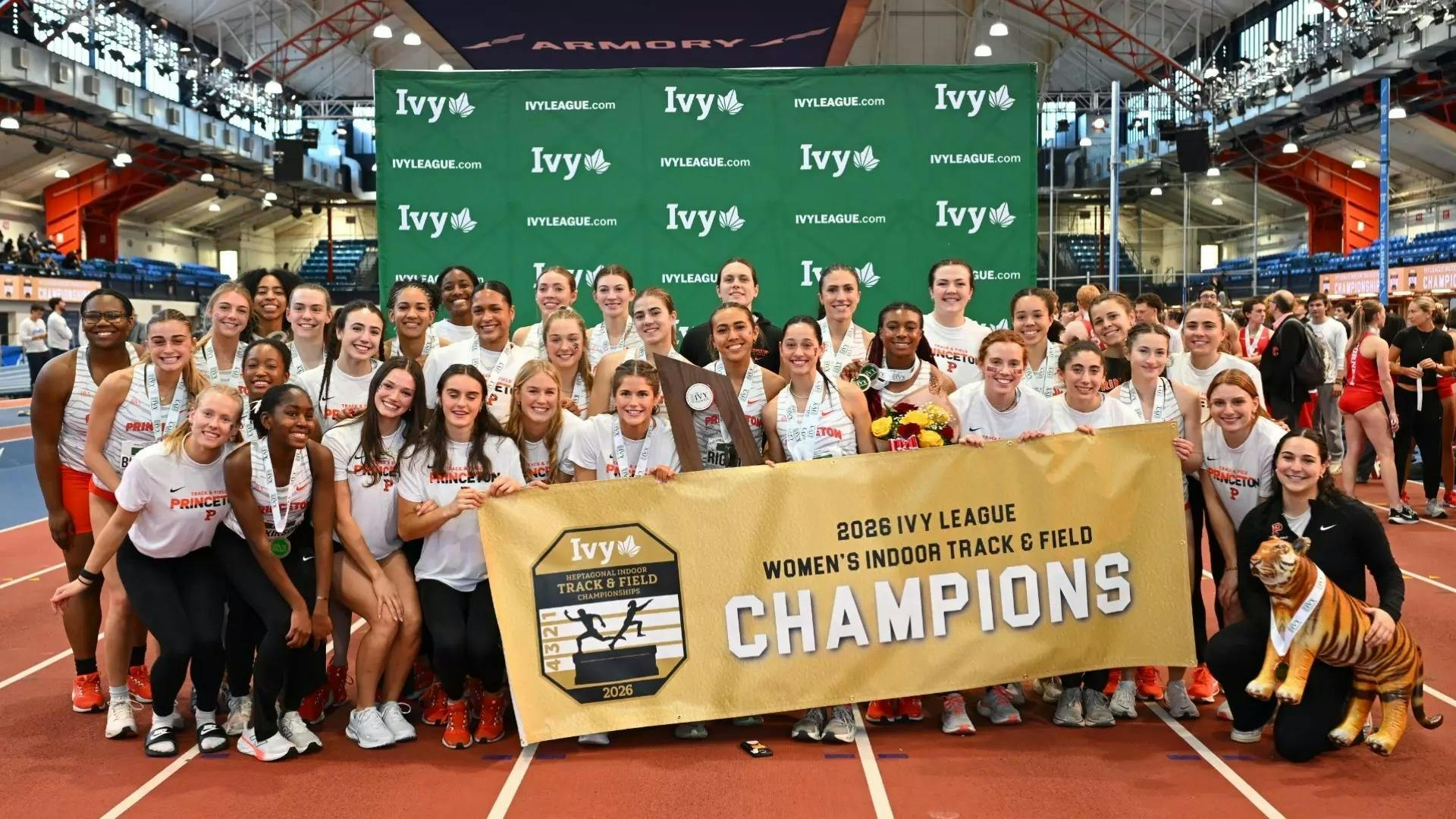 Women's track team stands with championship banner.