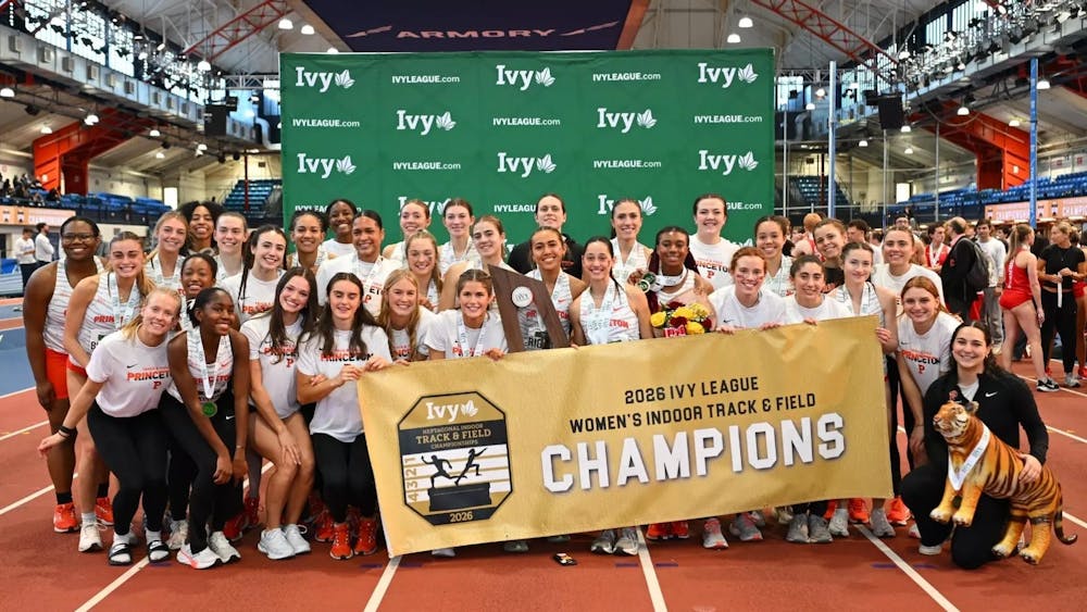 Women's track team stands with championship banner.
