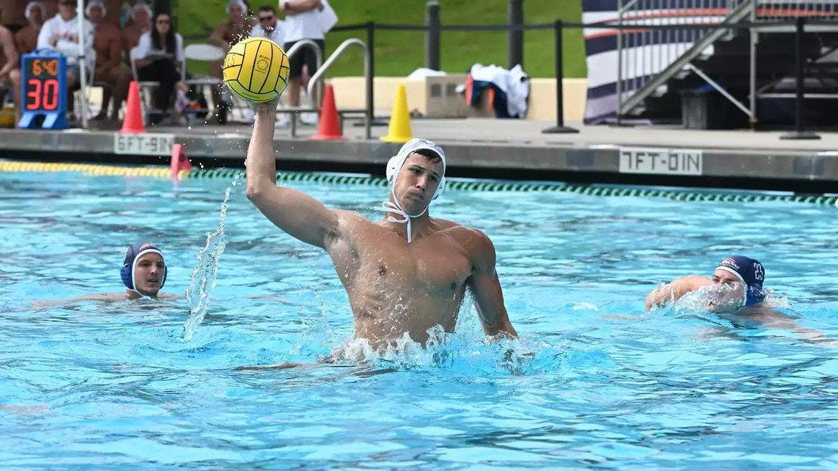 Man wearing white swim cap in pool hitting a yellow water polo ball.