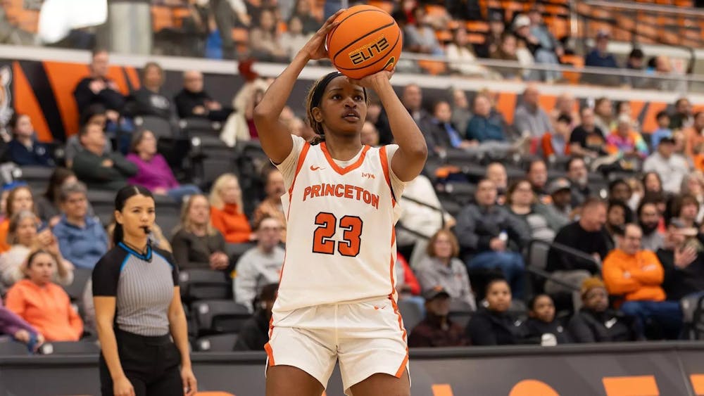 Princeton player in white jersey shooting basketball.