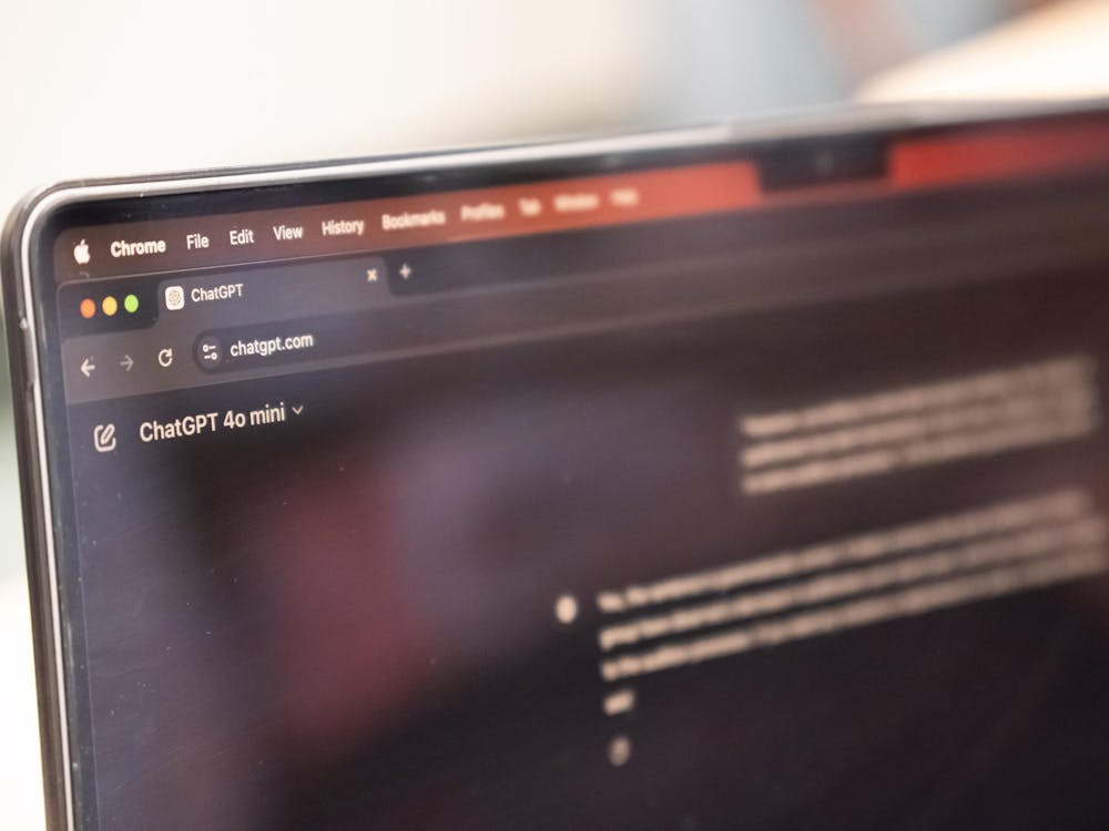 A computer screen opened to ChatGPT artificial intelligence program, with a white background behind the computer.