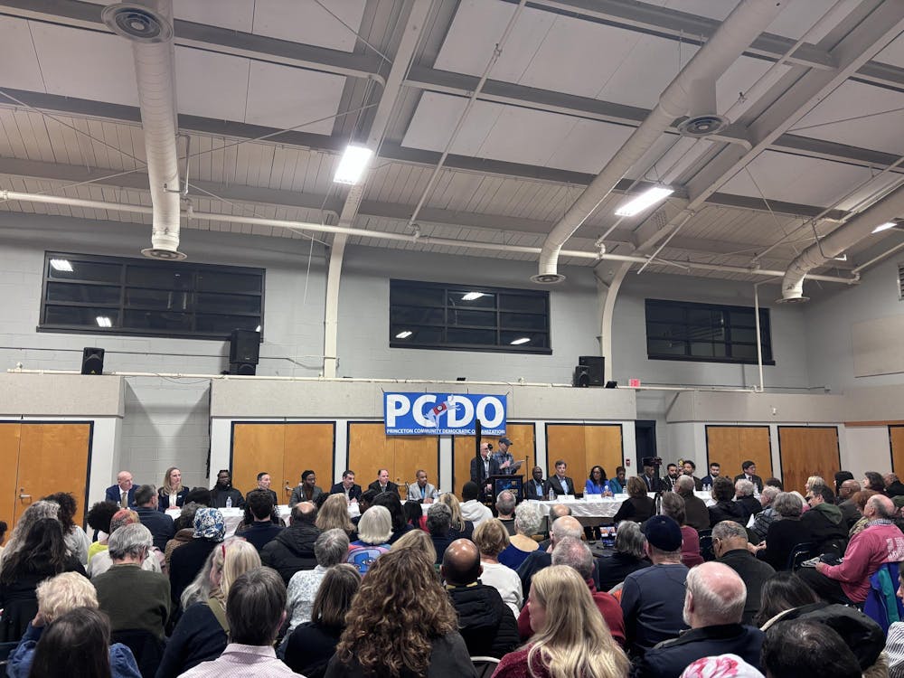 A crowd faces a stage with seated candidates. There is a podium in the middle of the stage, as well as a PCDO banner above it. 