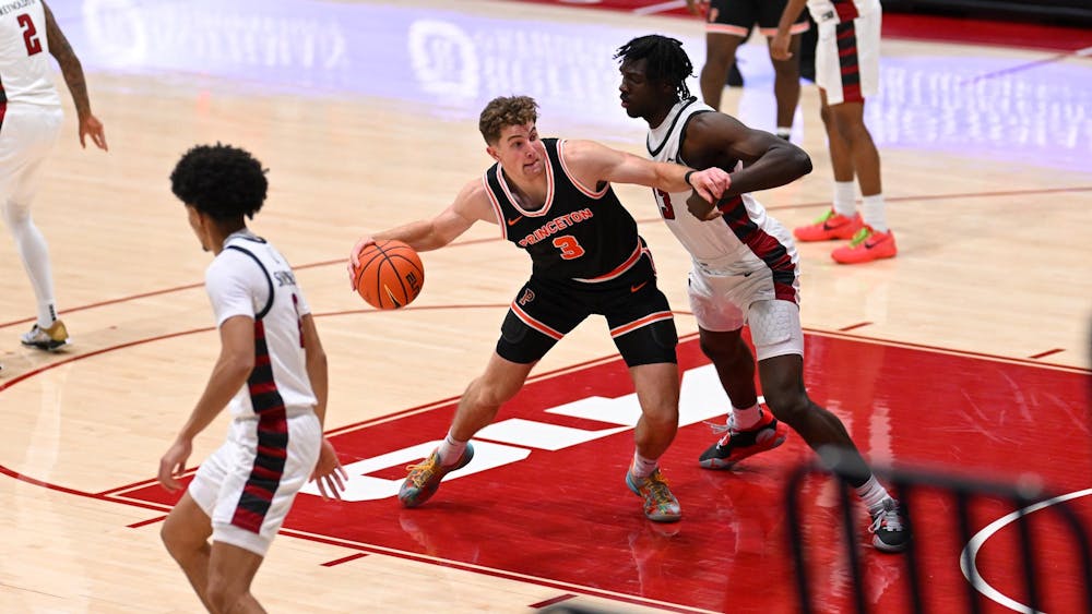 A man dribbles a basketball as he works against a defender on a basketball court. 