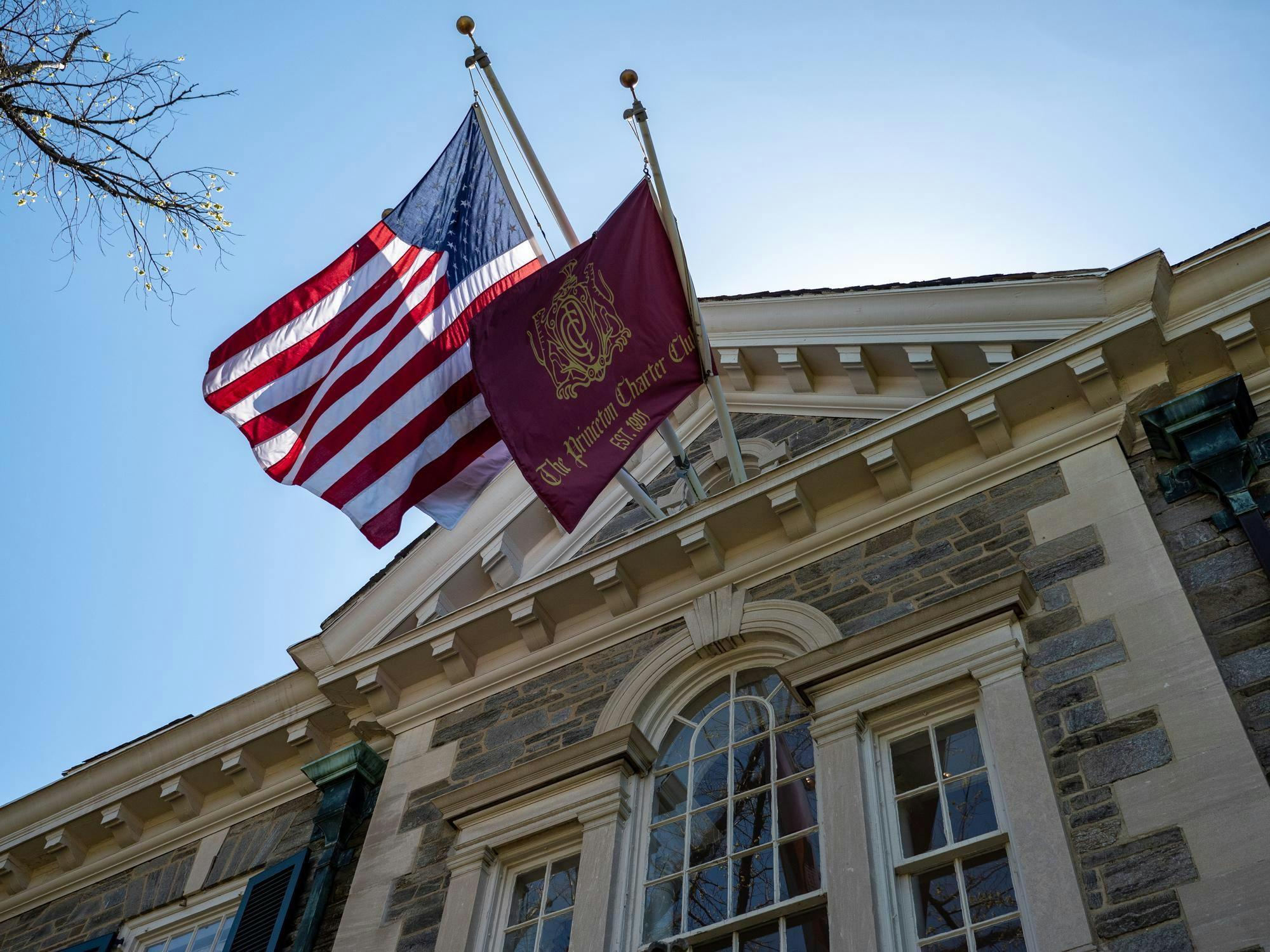 entrance to Charter Club, a gray stone building with two flags under a blue sky.