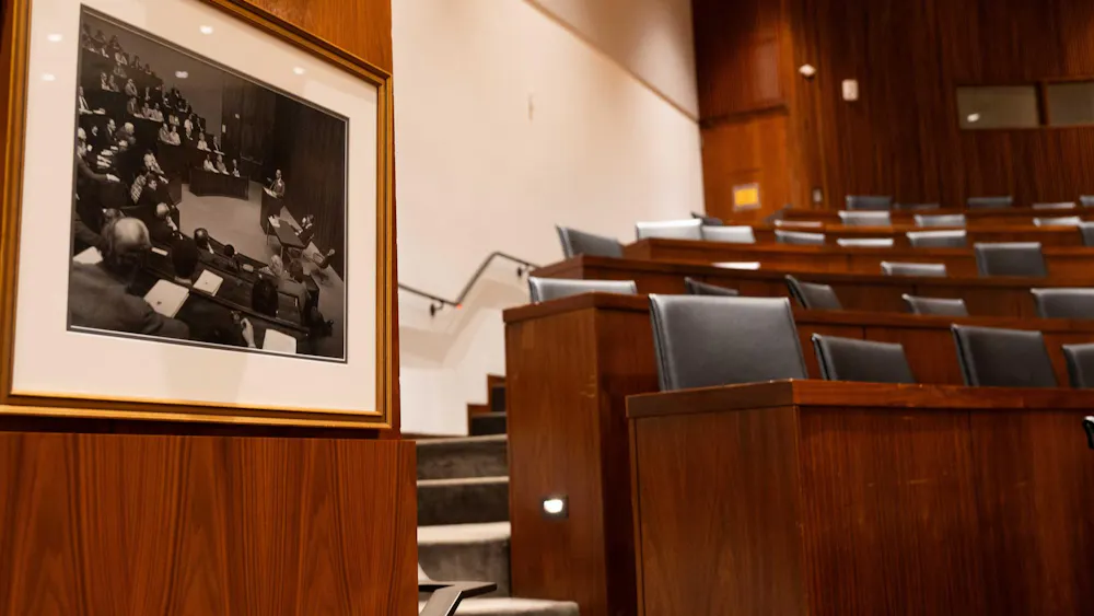 A room with brown tables and black chairs is shown. On the left is a photo hanging showing the room full.