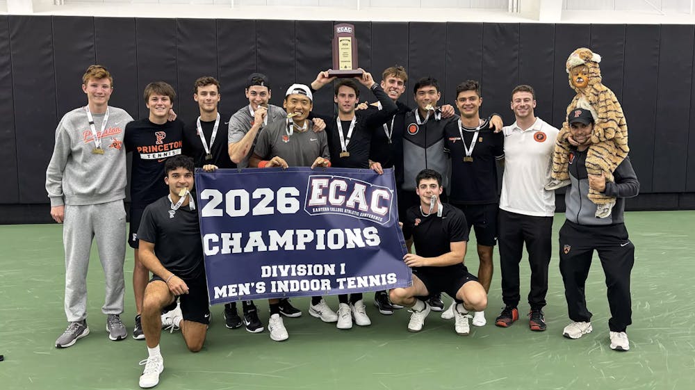 A group of Princeton tennis players holding a poster that says ‘champions,’ and a player in the center of the photo is hoisting a trophy