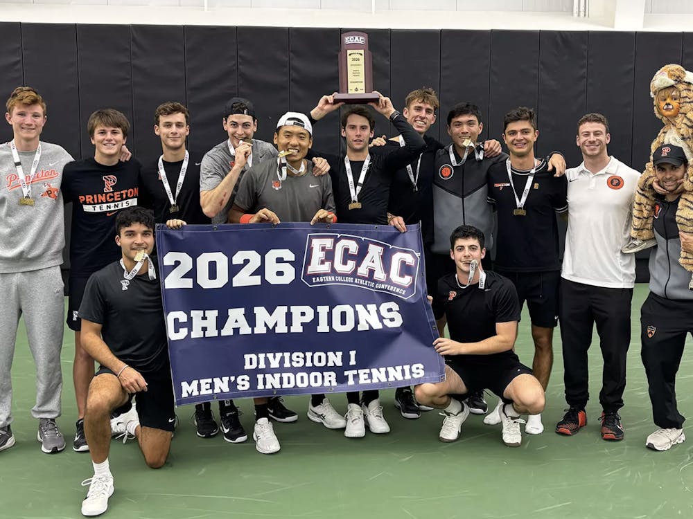 A group of Princeton tennis players holding a poster that says ‘champions,’ and a player in the center of the photo is hoisting a trophy