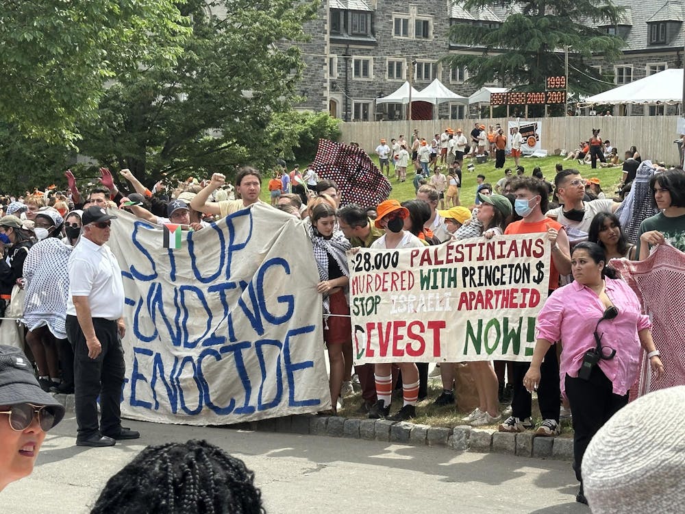 People on sidewalk holding up signs with phrases such as “STOP FUNDING GENOCIDE.”
