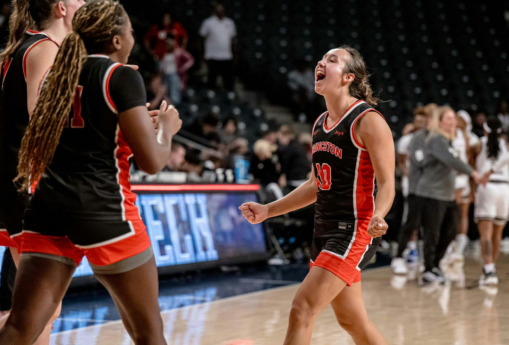 Players in black and orange basketball jerseys celebrate.