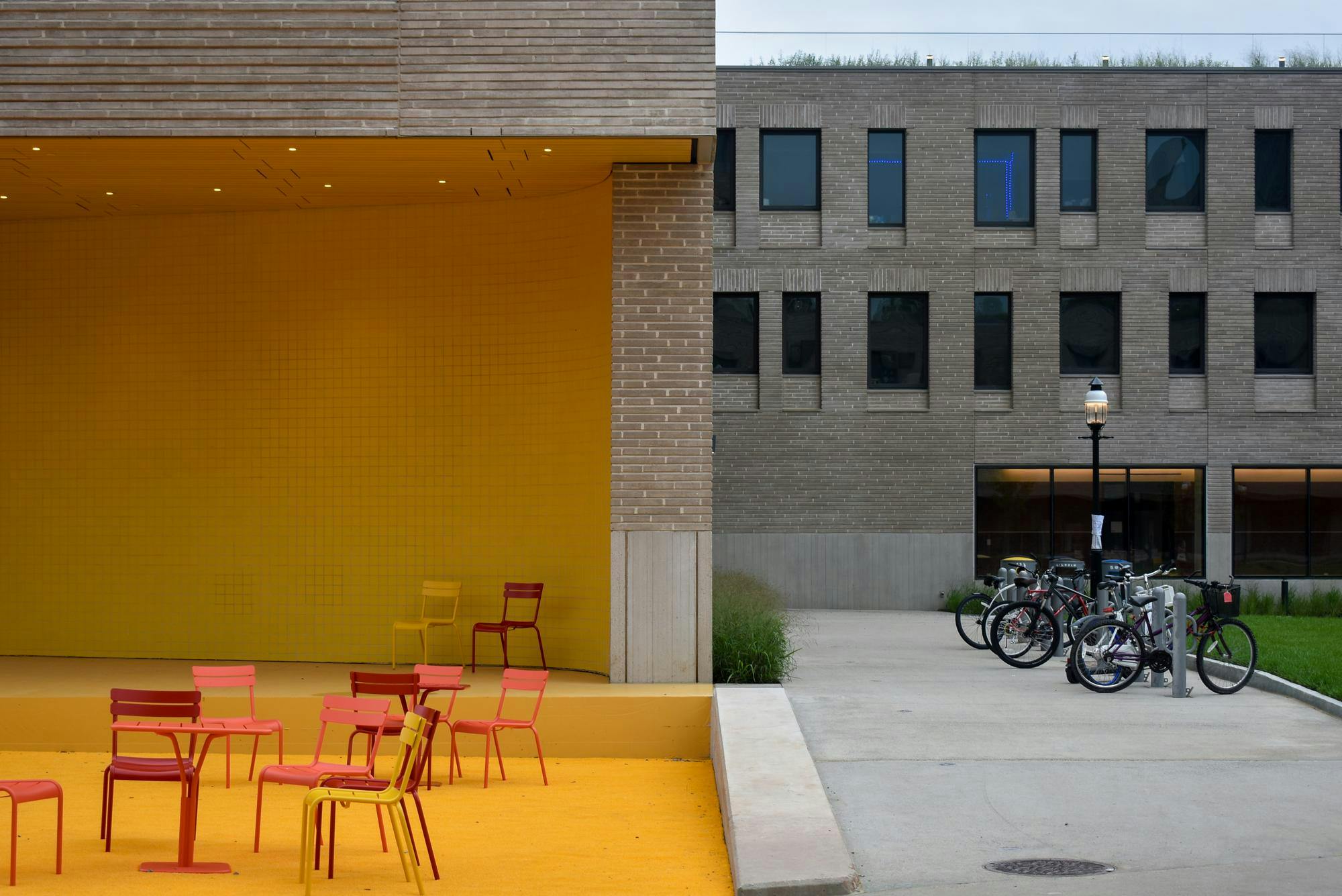 A grey brick building with a bright yellow stage on the right side.