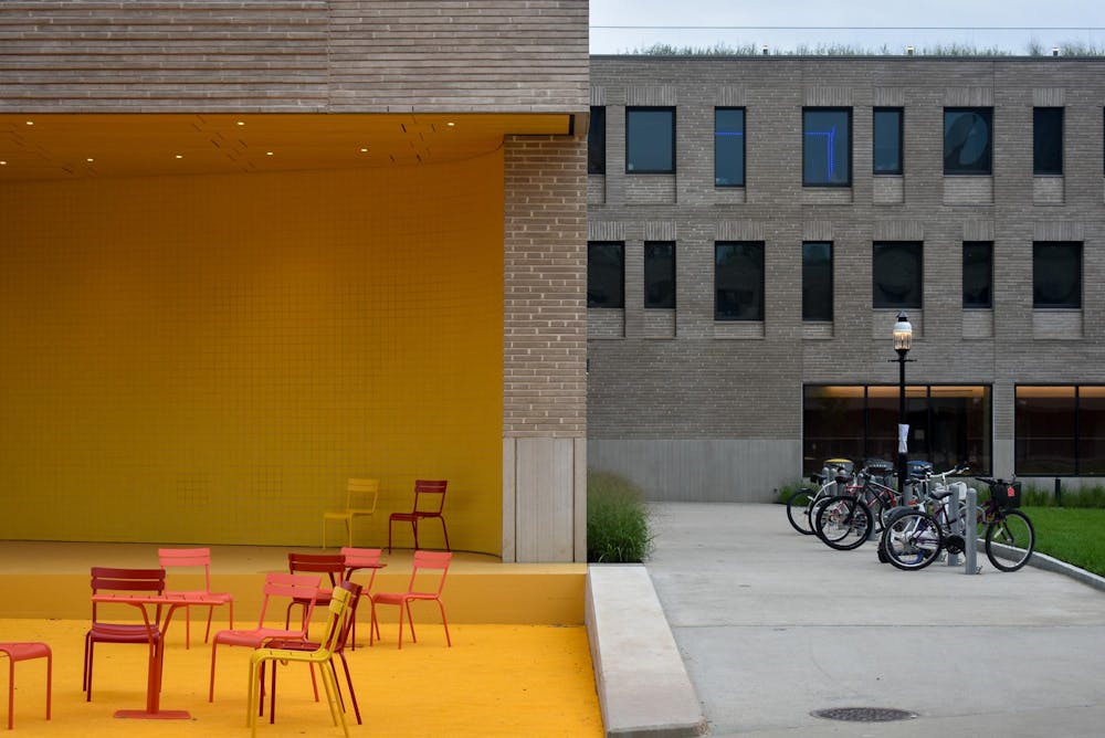 A grey brick building with a bright yellow stage on the right side.