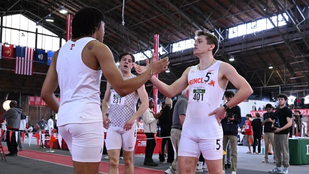 Two Princeton track athletes high-five each other. 