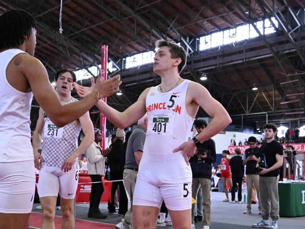 Two Princeton track athletes high-five each other.