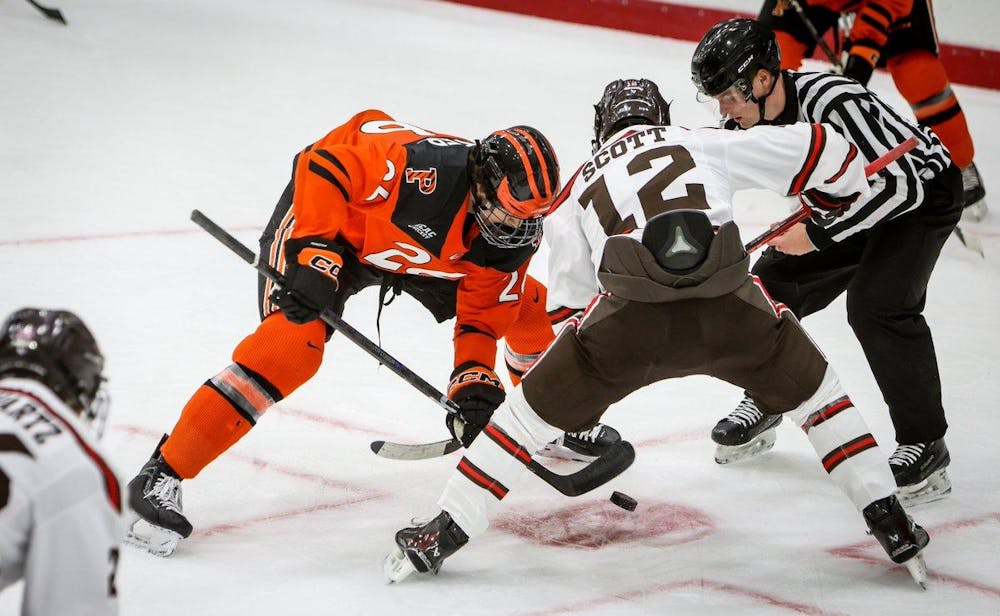 Princeton and Brown hockey players lean in for a faceoff during a hockey game. 