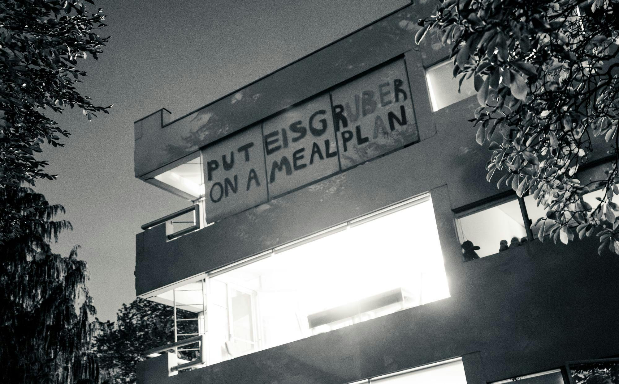 A banner with “Put Eisgruber on a meal plan” written on it hanging on the window of a building
