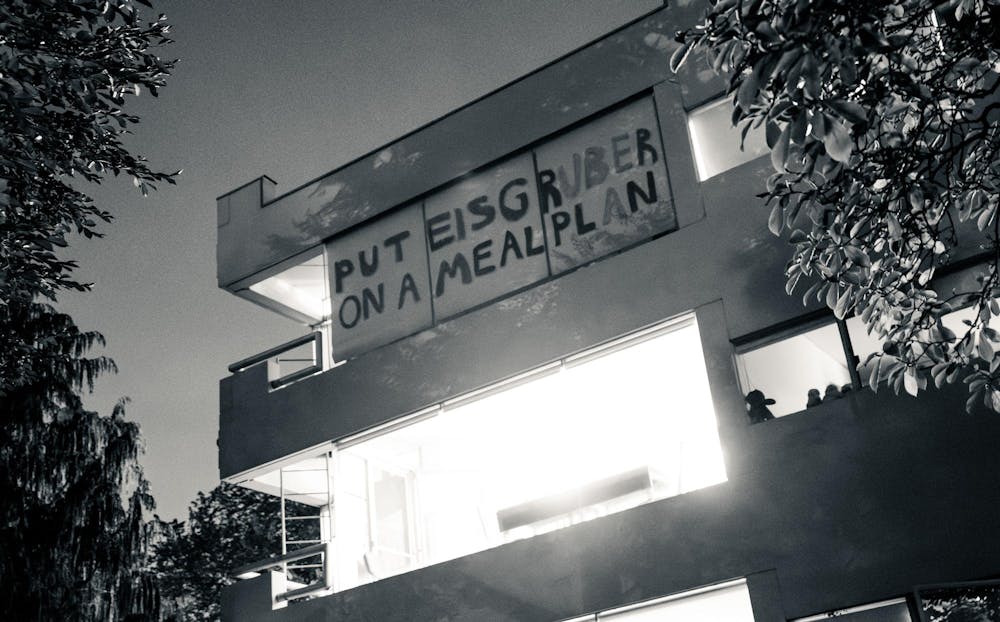 A banner with “Put Eisgruber on a meal plan” written on it hanging on the window of a building