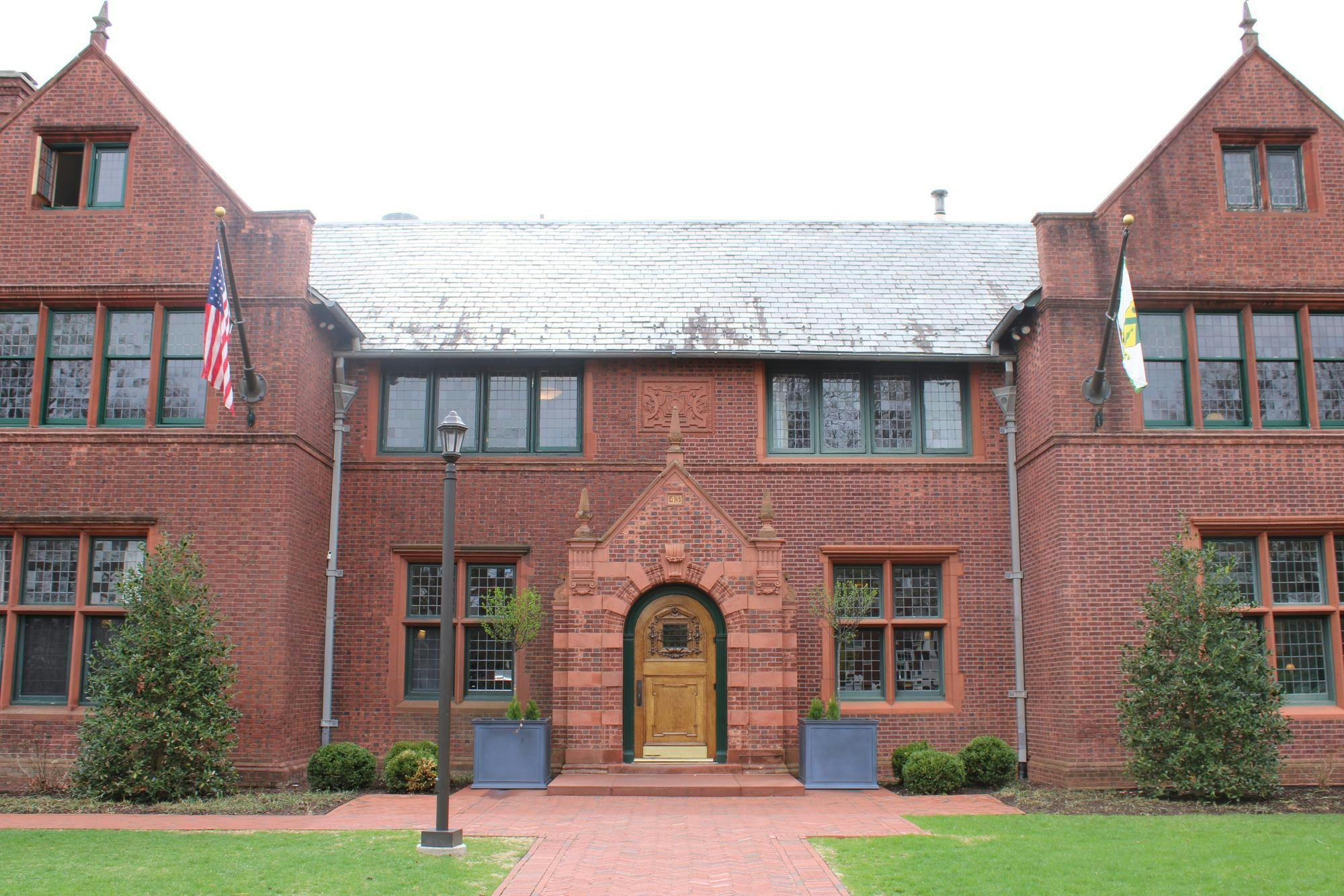 A red brick building with a decorative entrance and flags hanging above each side of the door. 