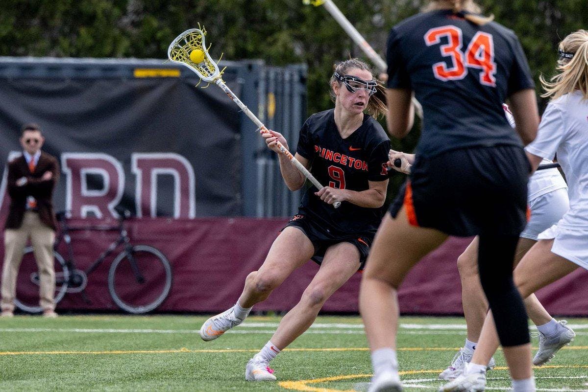A woman holding a stick in her hand on a lacrosse field as she looks to make an offensive move. 