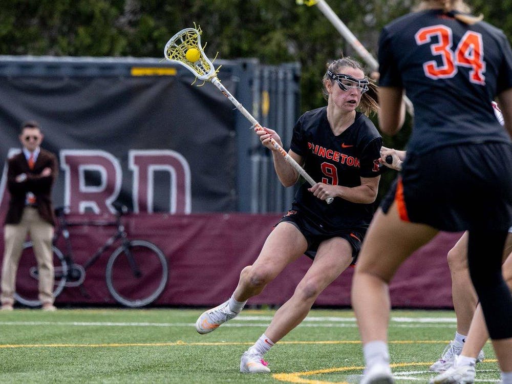 A woman holding a stick in her hand on a lacrosse field as she looks to make an offensive move. 