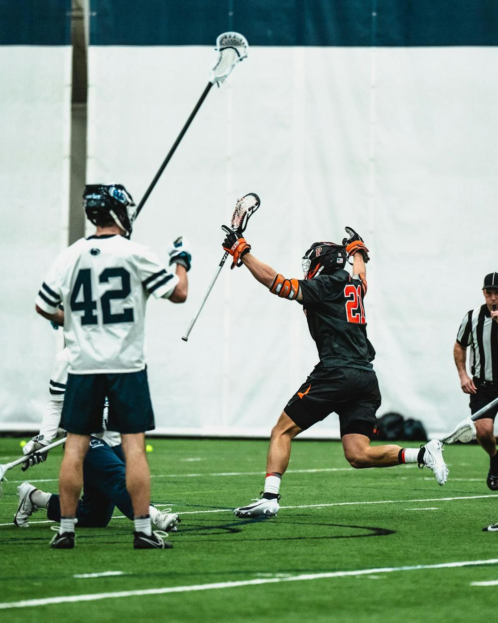 Player in black raises his arms in celebration while a player in white stands still to the first player's left.