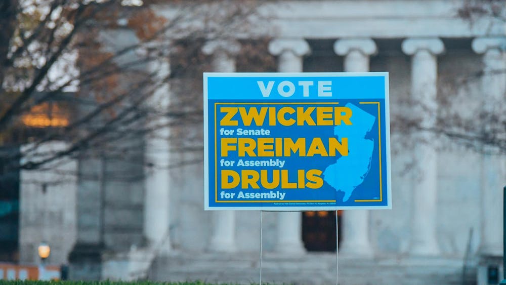 Blue sign advertising political candidates stands against a white marble building.