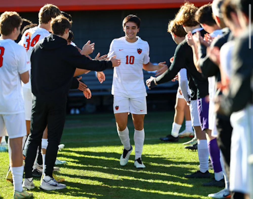 A player in white jersey walks through his teammates lined up.