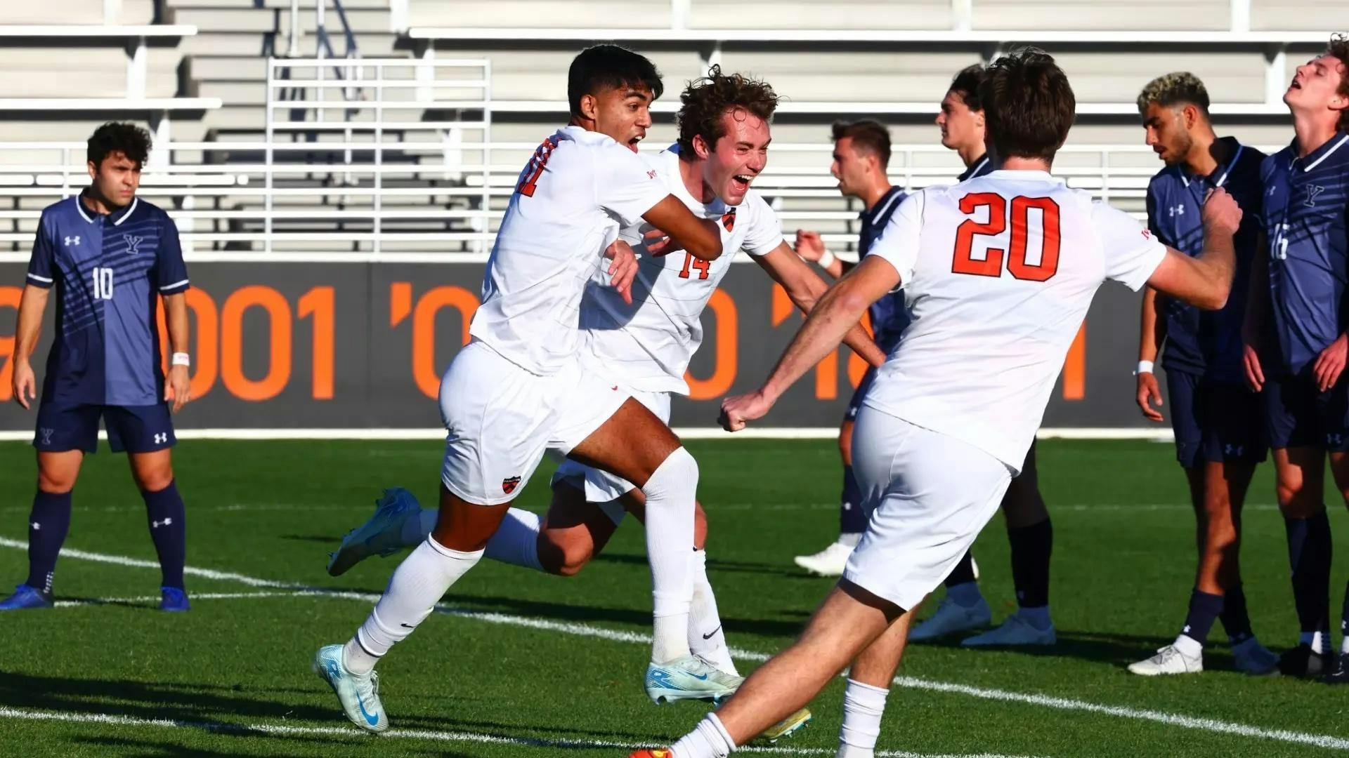 A goalscorer celebrates with teammates after kicking the ball in the net