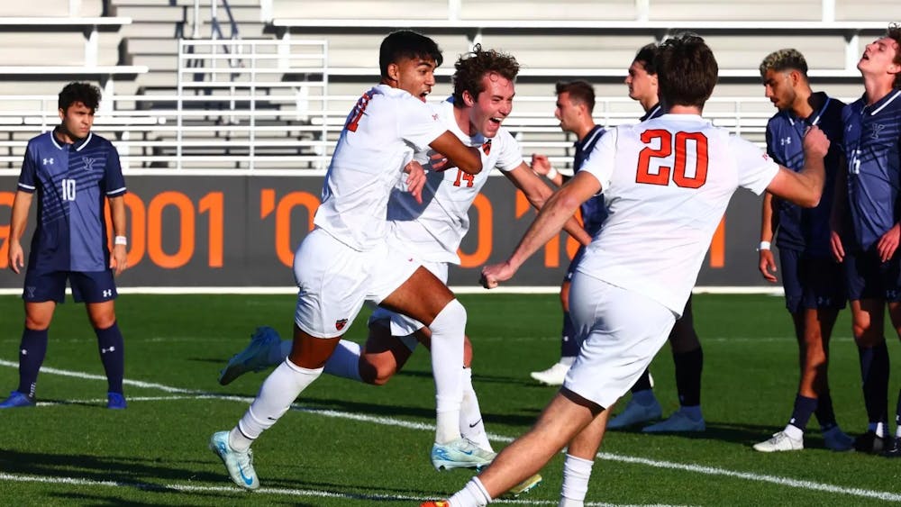 A goalscorer celebrates with teammates after kicking the ball in the net