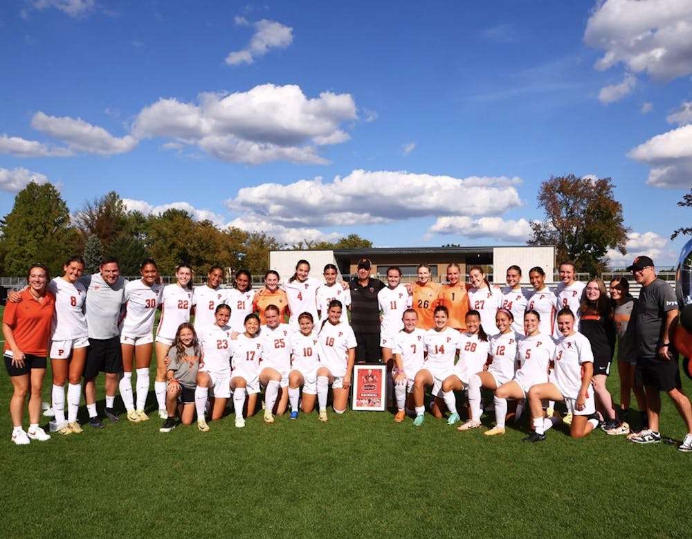 The women's soccer team poses for a photo commemorating the 100th career win of the coach 