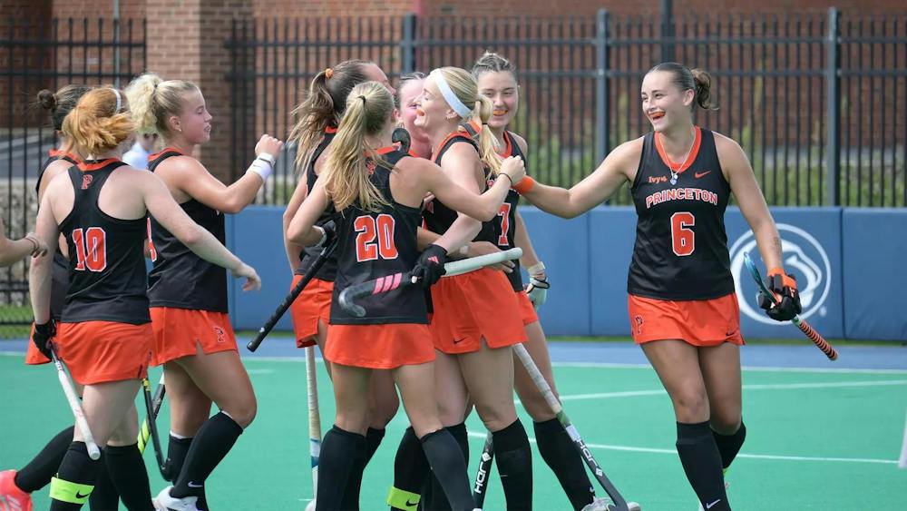 A group of women in black and orange jerseys smile and celebrate.