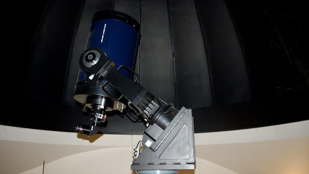 Un telescopio azul marino señala al techo en un cuarto vacío.