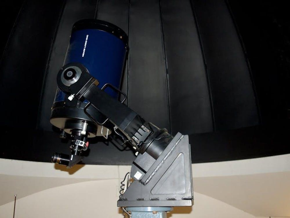 Un telescopio azul marino señala al techo en un cuarto vacío.