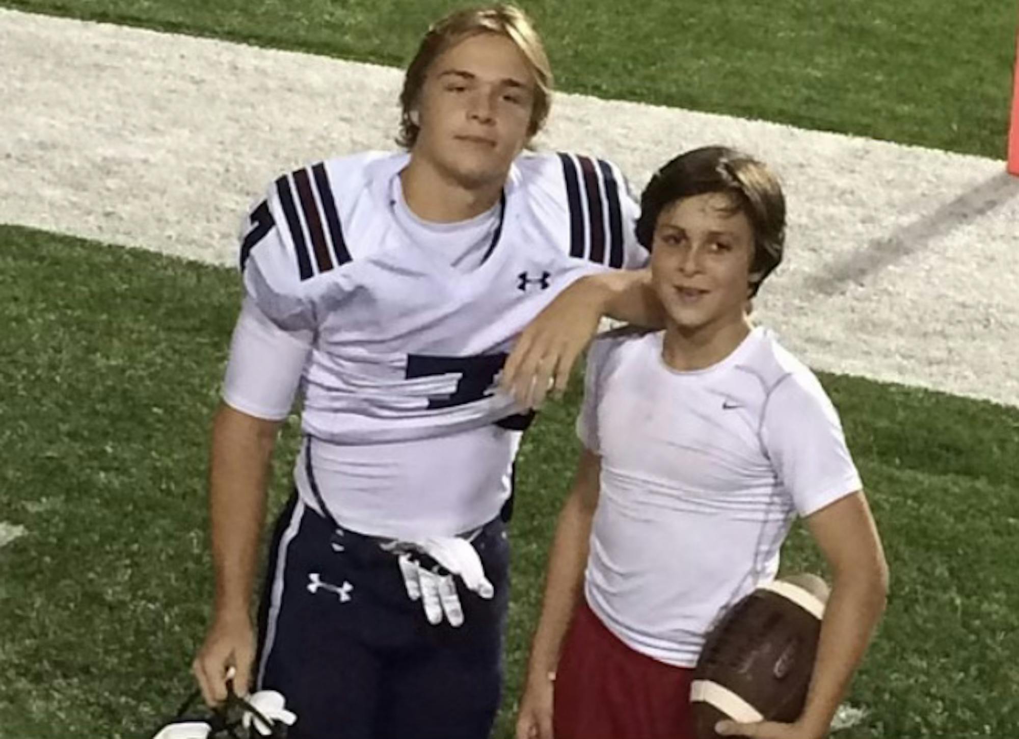 Tiger Bech, in football uniform, stands to the left of his brother and has his arm on his brother's shoulder. They both face the camera.