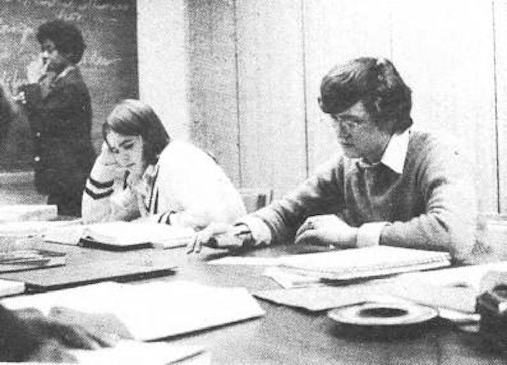 A black and white photograph of a man and woman seated next to each other looking at their open books during a precept discussion.