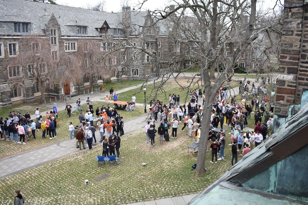 A wide angle photo of students gathered outside on the grass in front of dorm buildings in Rockefeller and Mathey Colleges.