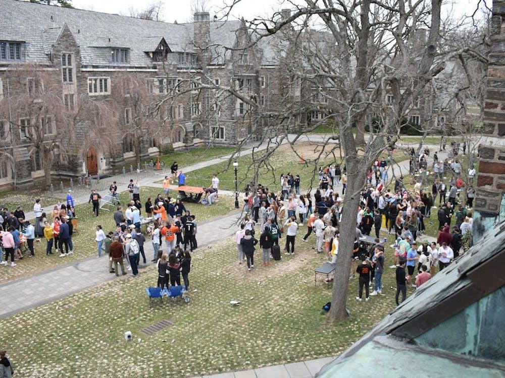 A wide angle photo of students gathered outside on the grass in front of dorm buildings in Rockefeller and Mathey Colleges.