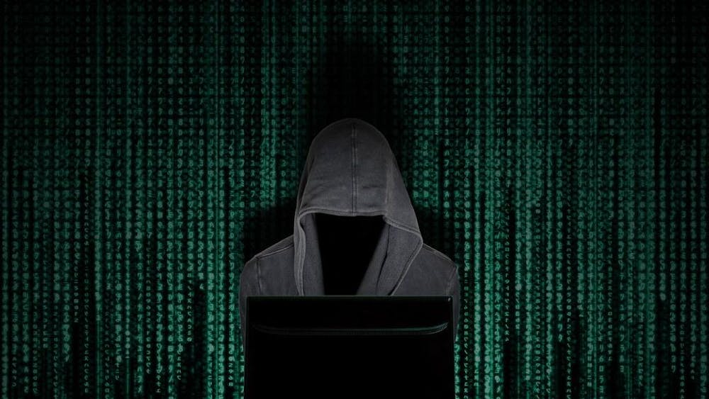 Hooded figure hacking into a computer.