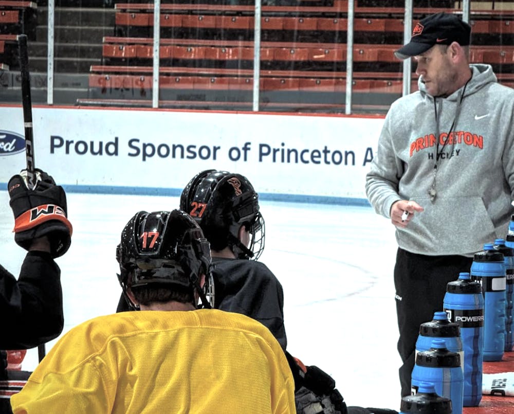 Men's head coach Ben Syer coaching his players on the ice. 