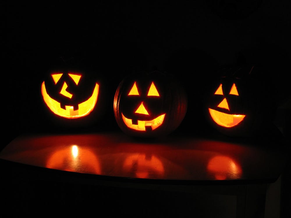 Three jack-o-lanterns with smiley faces in the dark.