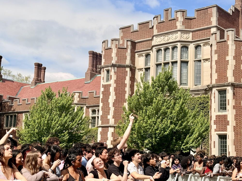 Crowd full of students behind a silver rail stand with a red brick building in the background. 