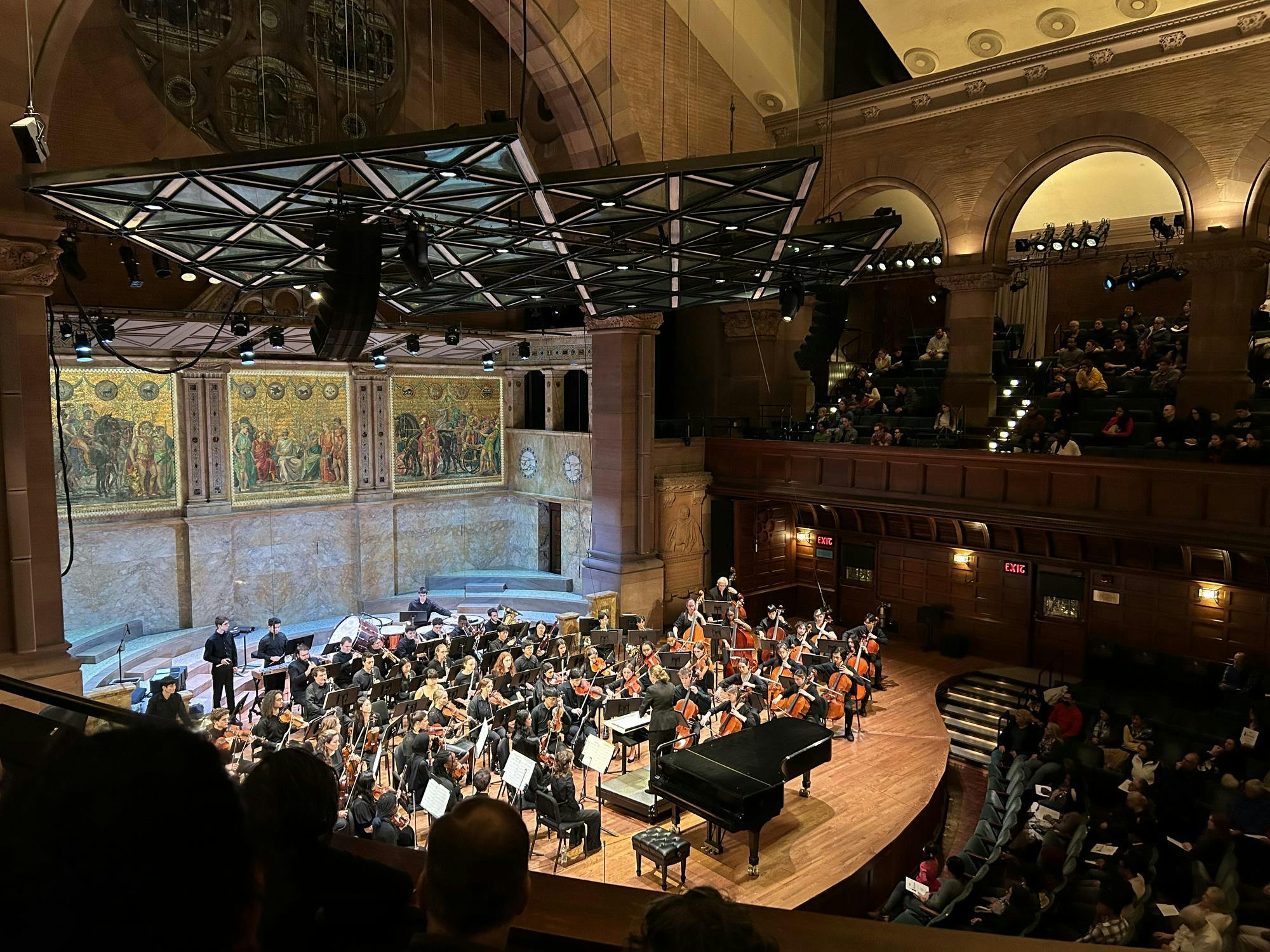 An aerial view of an orchestra on stage under a spotlight.