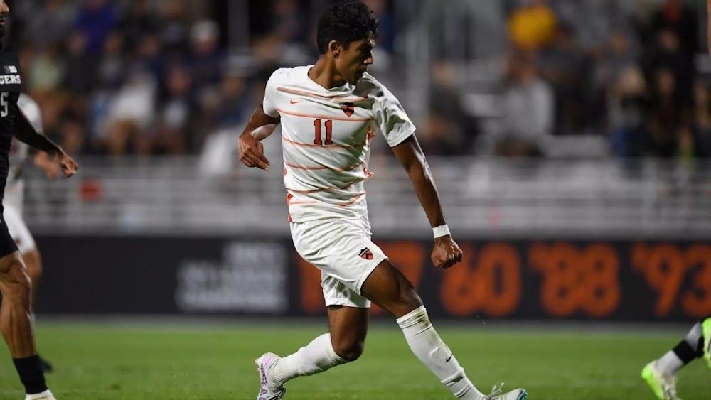 A man in a white striped jersey looks to shoot a soccer ball.