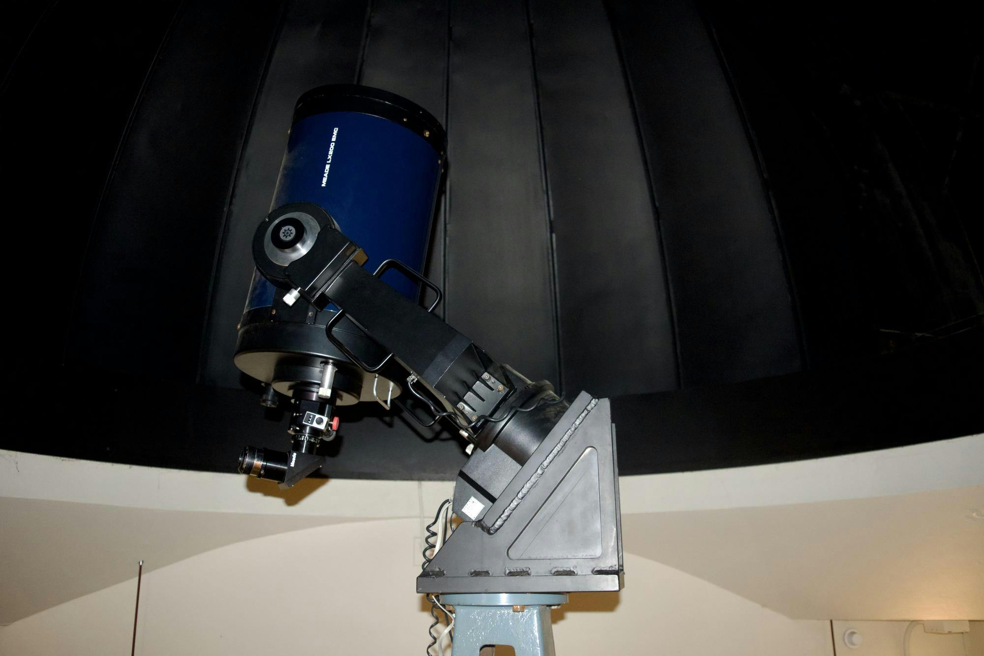 A navy blue telescope points toward the ceiling in an empty room. 