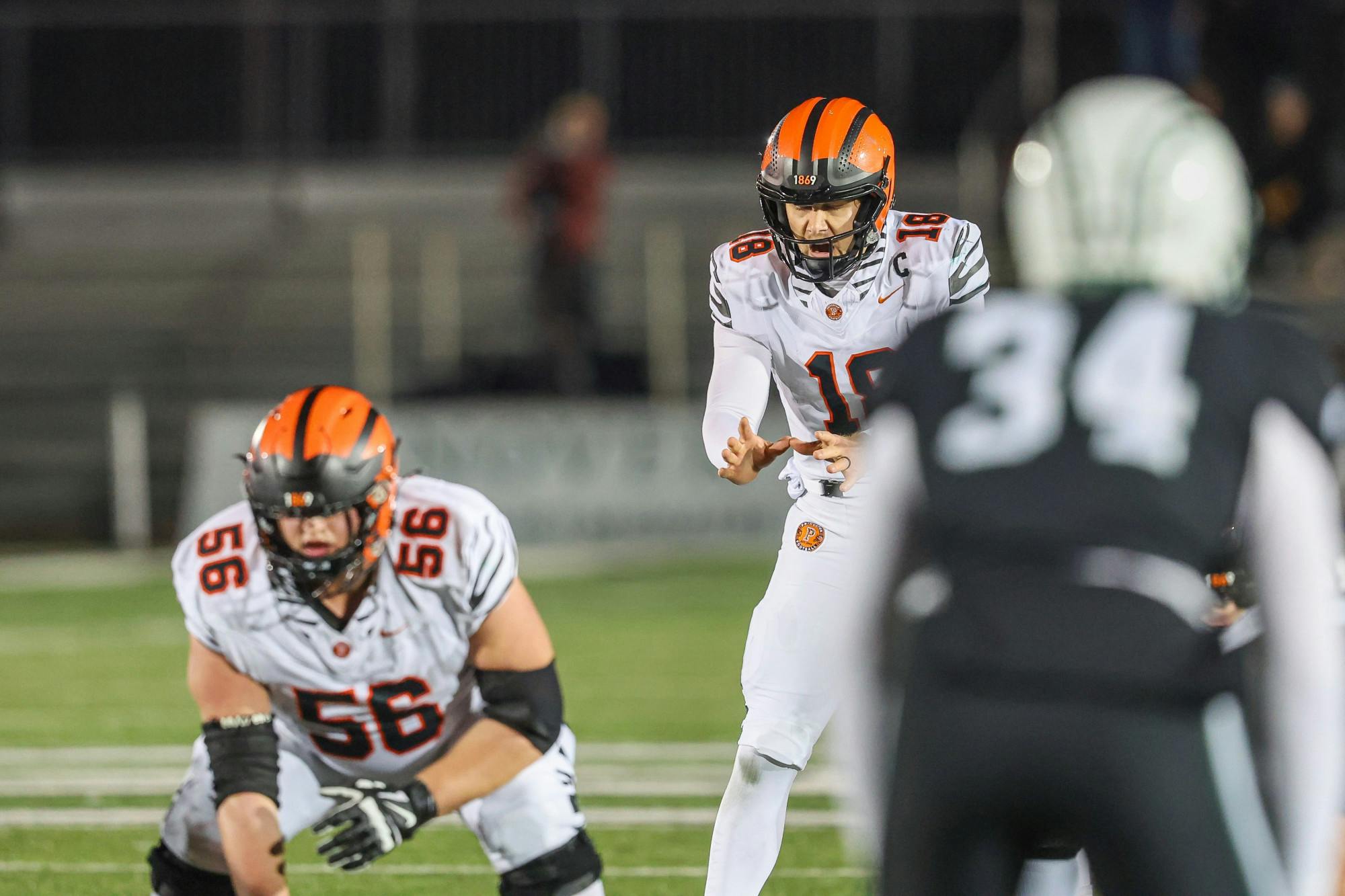 A man kneeling down as another man behind him is yelling with his hands together. 