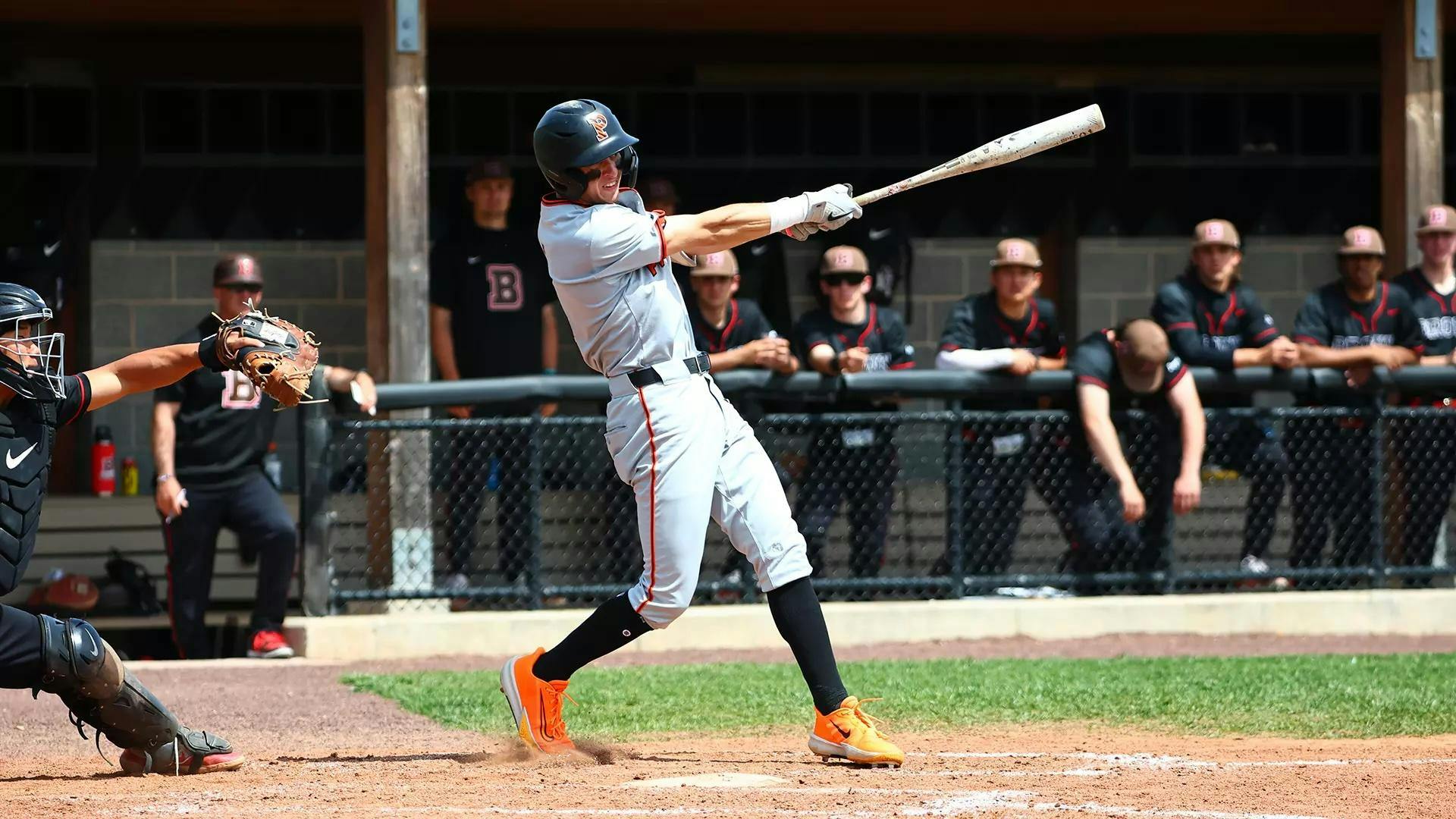 Man in grey Princeton uniform swings bat in batter's box.