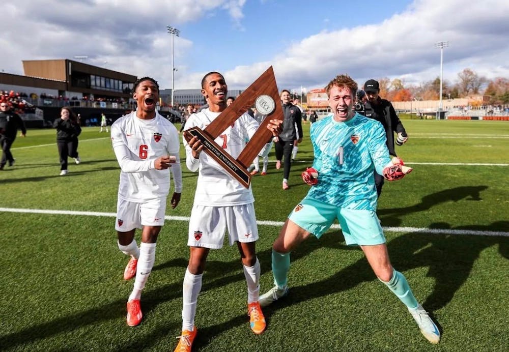 Three soccer players celebrating with trophy.